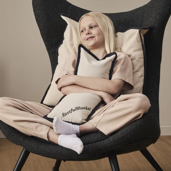 Tyngdepude Tryghedspude 3 kg plastfri lifestyle i brug Kvinde bruger Tyngdepude Tryghedspude 3 kg i skødet fra RestfulBlanket for roligt og stabilt tryk.